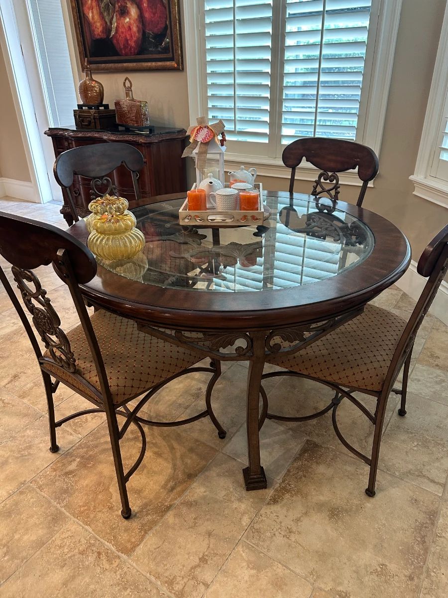 Round Dining Table with Ornate Metal Base and Upholstered Chairs