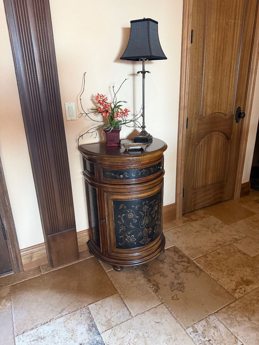 Carved Accent Cabinet with Lamp and Floral Arrangement